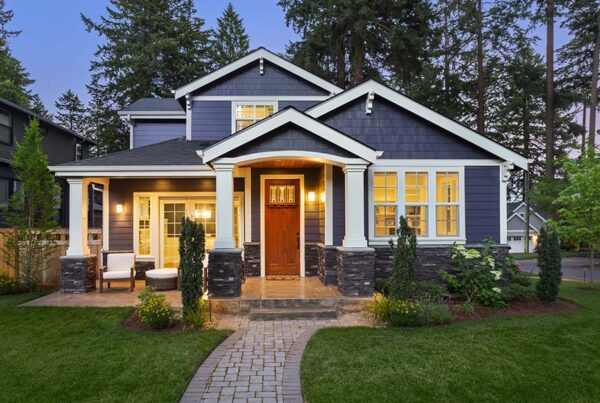 5 Interesting Facts About Home Insurance - View of a Single Family Two Story Home in the Evening with the Lights on and Clean Cut Green Grass